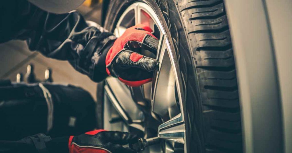 a person putting a wheel back after performing brake car maintenance