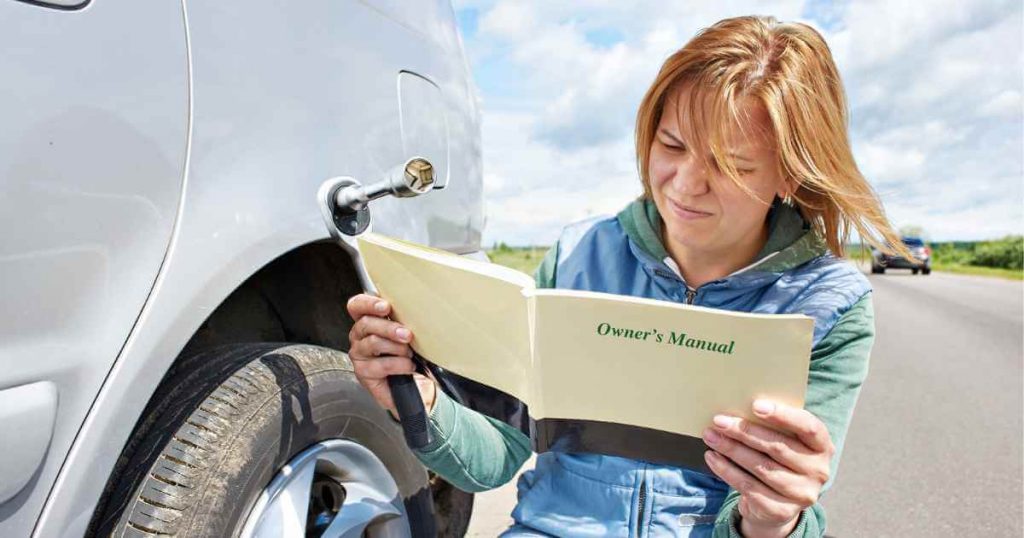 a woman on the side of the road next to her used car as she reads the owner's manual