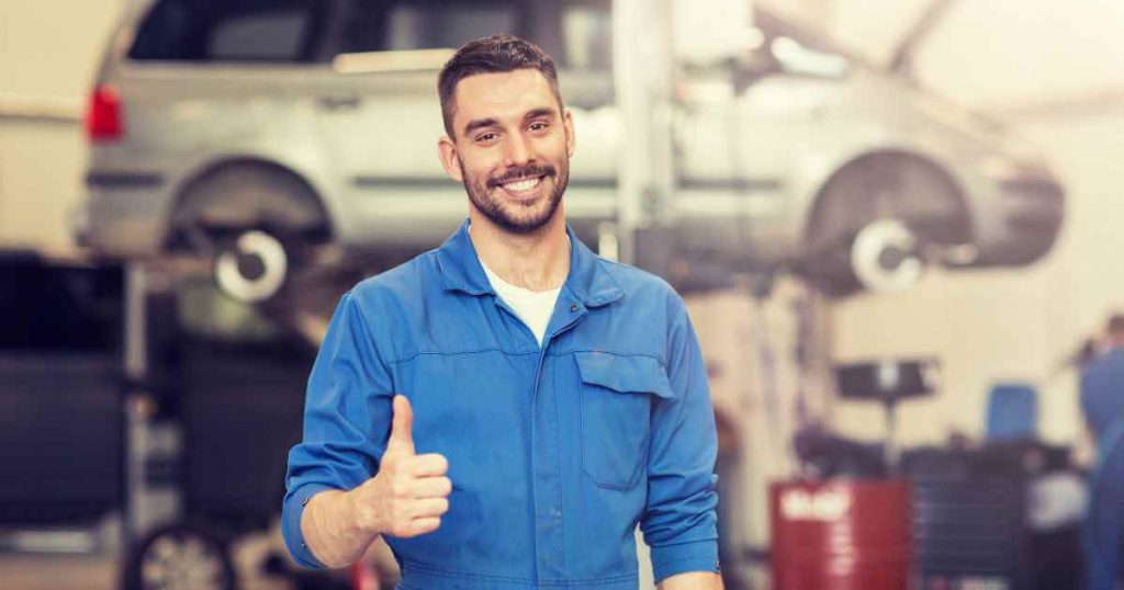 a car mechanic smiling and giving a thumbs up depicting a reliable car repair shop that can perform car maintenance