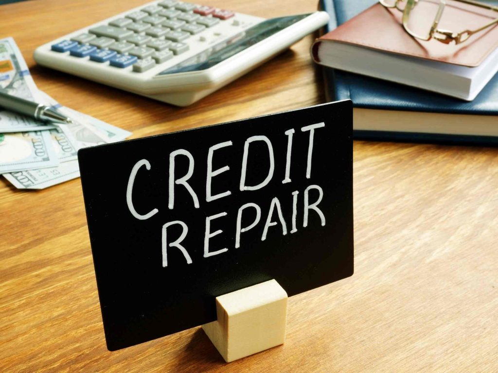 A sign on a desk that says credit repair next to some books, calculator, and money relating to buying used cars