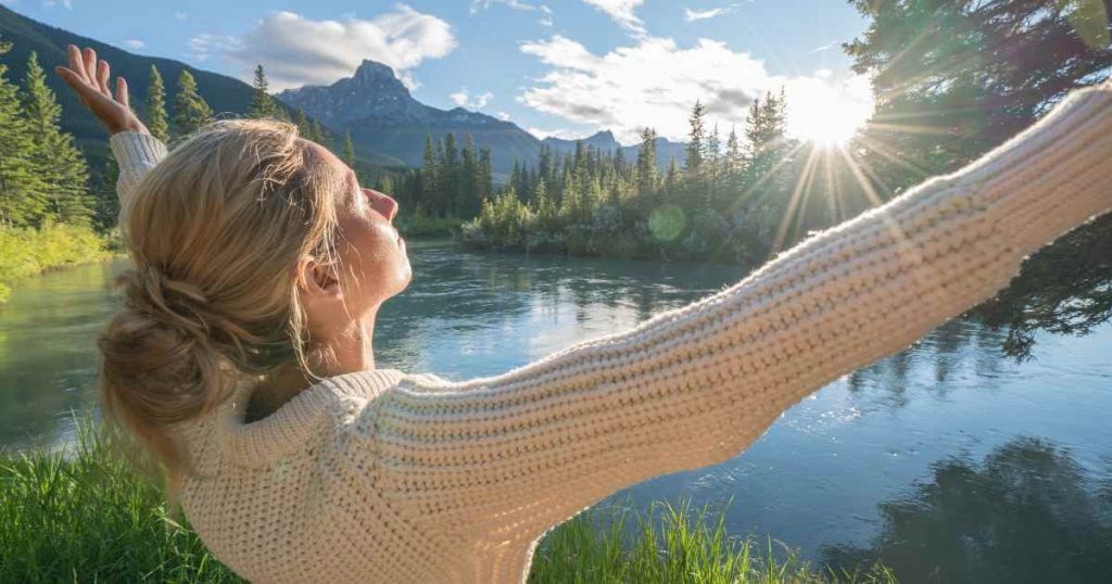 a woman by a beautiful lake with her arms stretched wide as she embraces the benefits of no license car lots near me