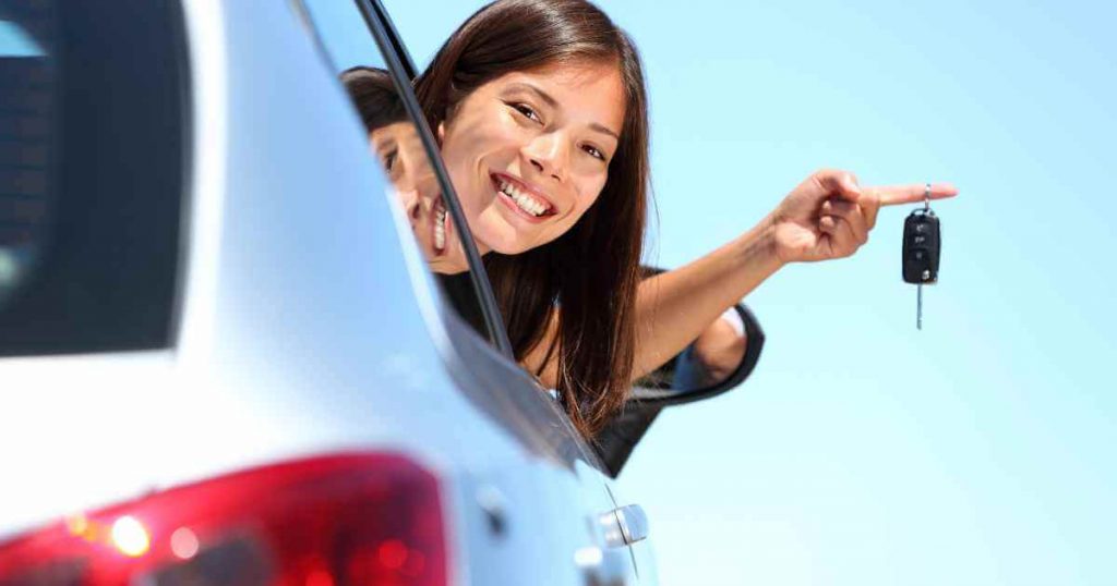 a woman holding keys out of a car and smiling as she takes off from Fresno car lots