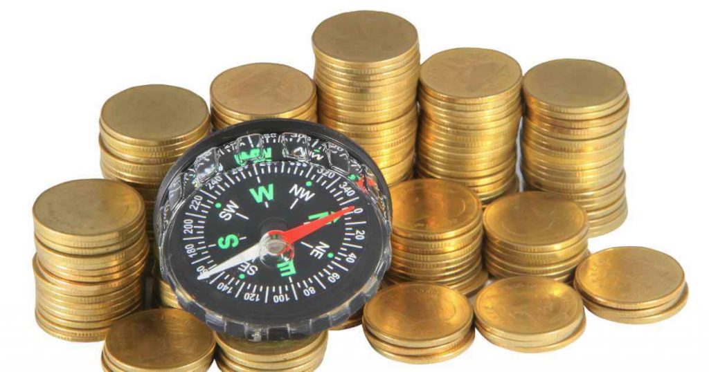 a few stacks of coins with a compass showing how to navigate your credit score for car loan approval
