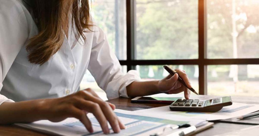 a woman sitting at a desk with a pencil and calculator trying to determine car loan interest rates