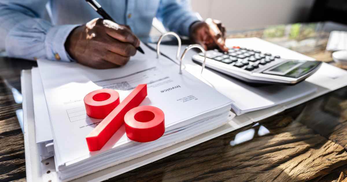 a man with a calculator and paperwork and a percentage symbol showing that he is calculating interest rate on a car loan