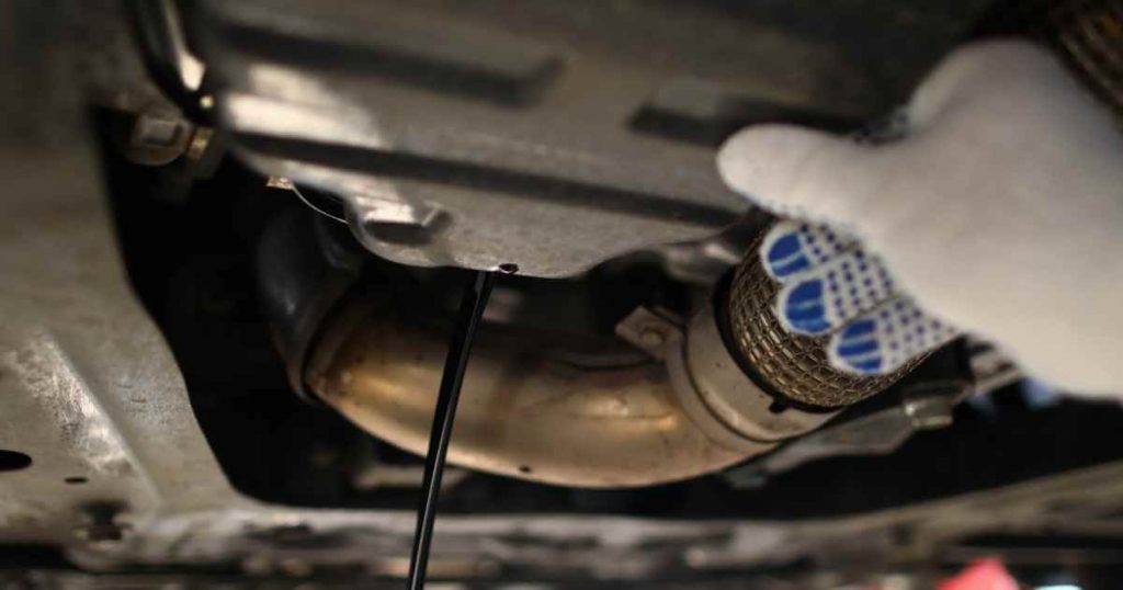 a hand reaching under the body of cars for sale to inspect the condition