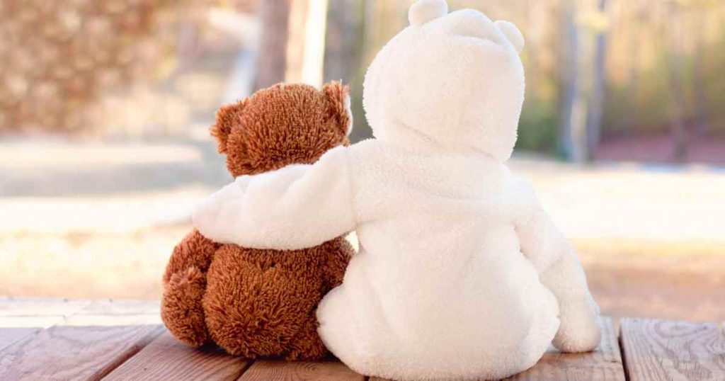 two teddy bears hugging as they look away