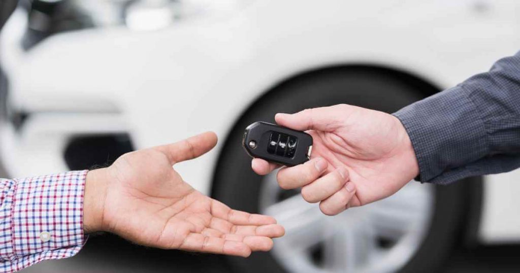 a man handing another man a set of used car keys