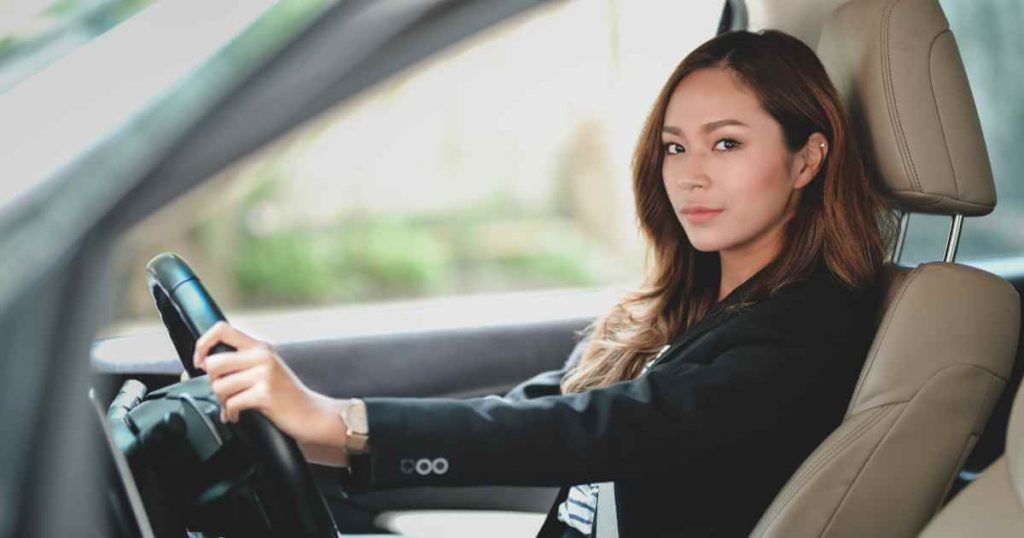 a confident woman in a car showing she has understood how calculating interest rate on a car loan can help her save