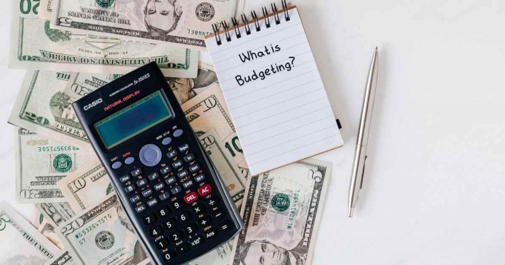 a calculator with money underneath and a notepad that reads what is budgeting? next to it