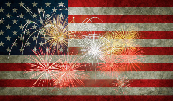 an American flag with fireworks firing in front of it