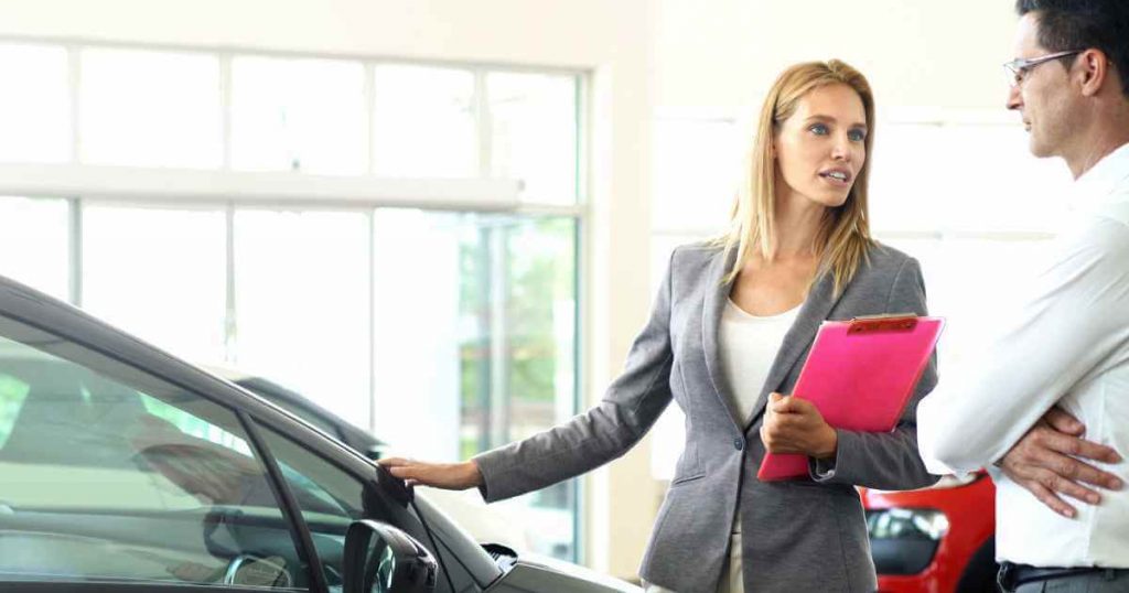 a woman showing a car to a customer to see if it is right for him