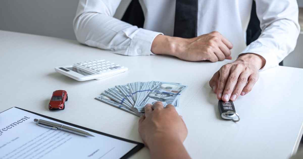 a man pushing over a down payment to another person pushing back car keys after buying through our car credit usa program