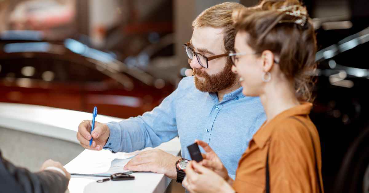 a man and woman signing a contract for cars plus credit vehicles