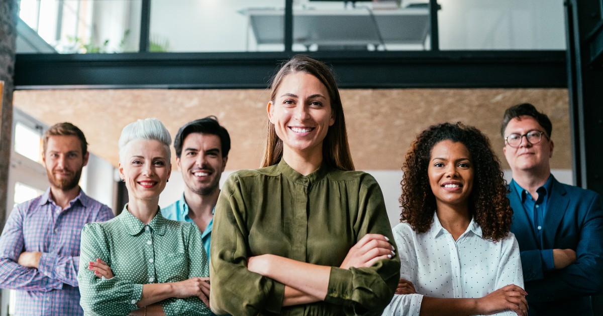 a confident and happy woman as the general manager with her team supporting her behind