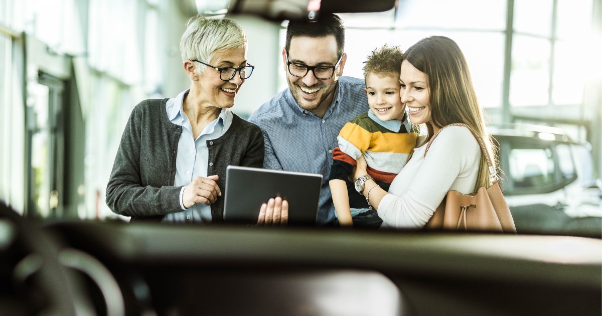 a salesperson consulting with a happy family as they purchase their next used car