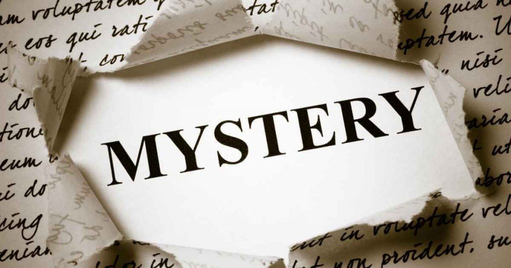 a piece of paper ripped open revealing the words "mystery" underneath