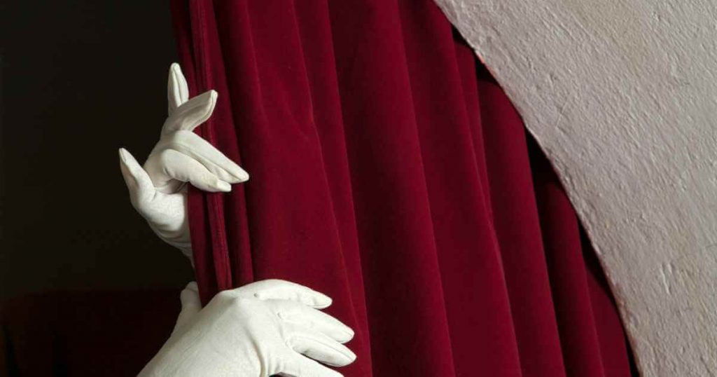 white gloved hands pulling back the curtains to unveil no credit car dealerships near me