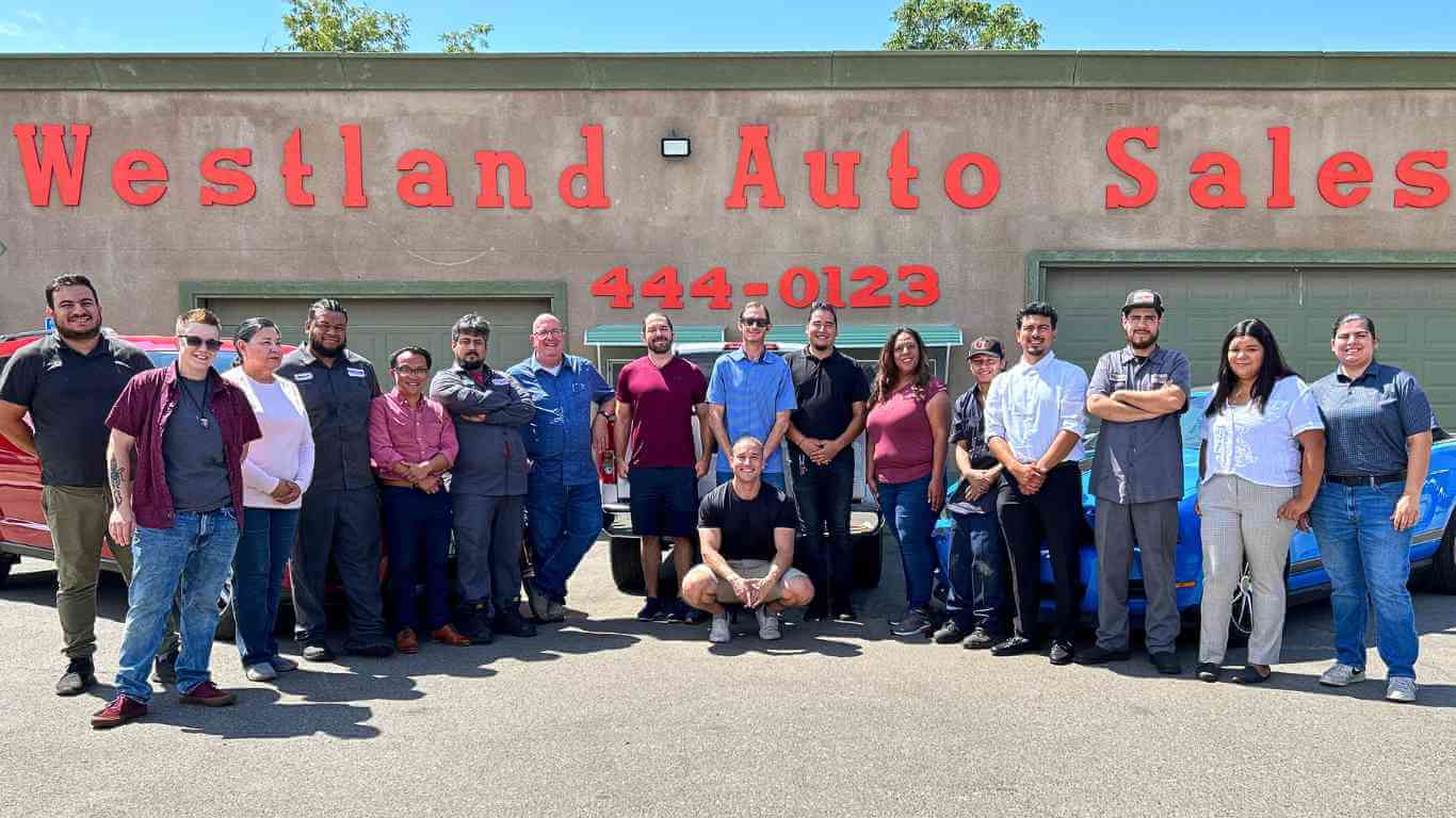 an image of Westland Auto Sale's entire staff smiling in front of their office and welcoming you into their buy here pay here near me program