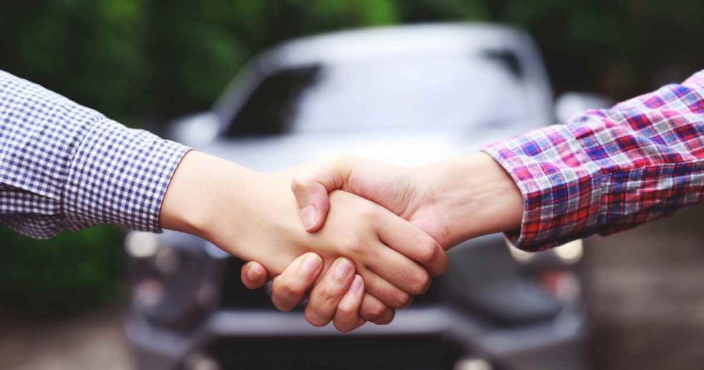 two people shaking hands after negotiating a good used car deal