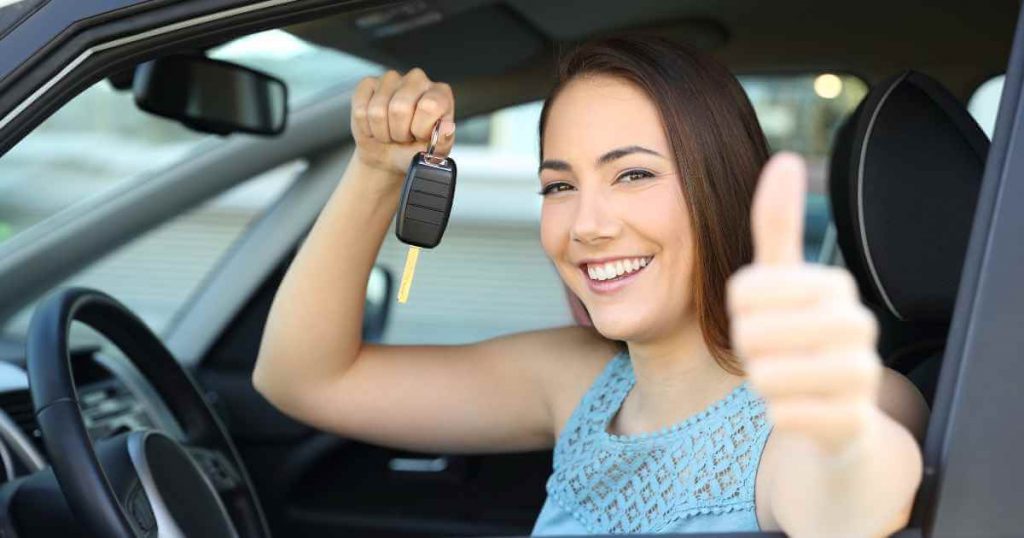 a happy woman holding up car keys and thumbs up after using our best practices when buying a used car