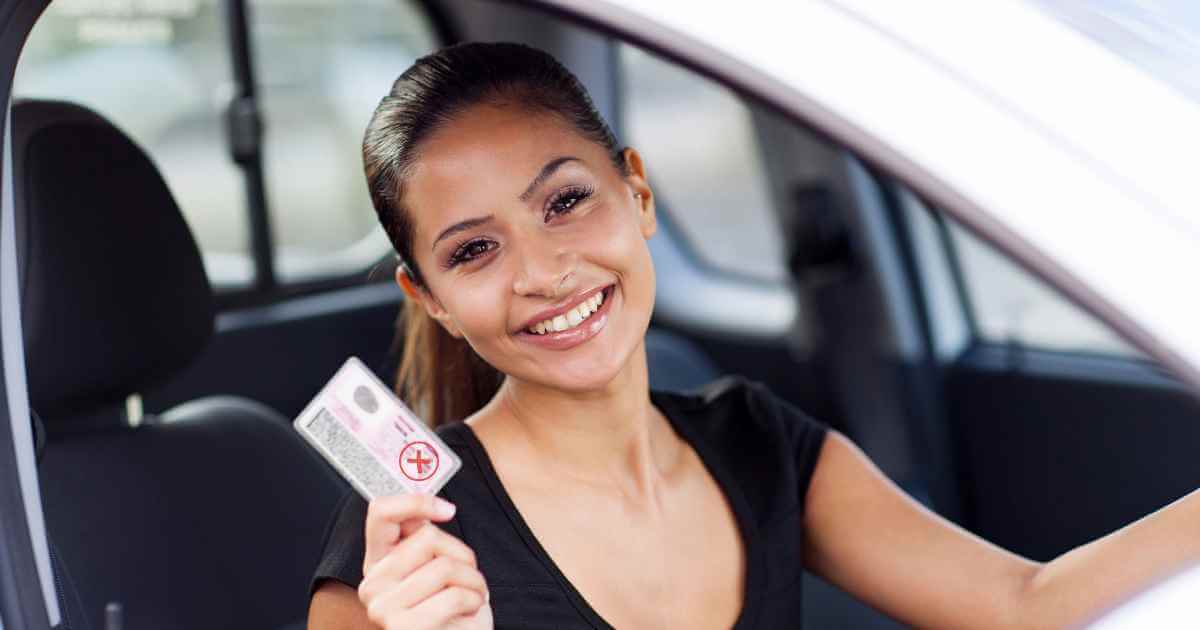 a woman in a car holding up her expired license after asking can i buy a car without a license