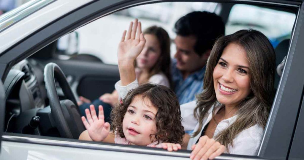 a happy family in a car after answer the question of can you trade in a car if you owe money on it and getting a car