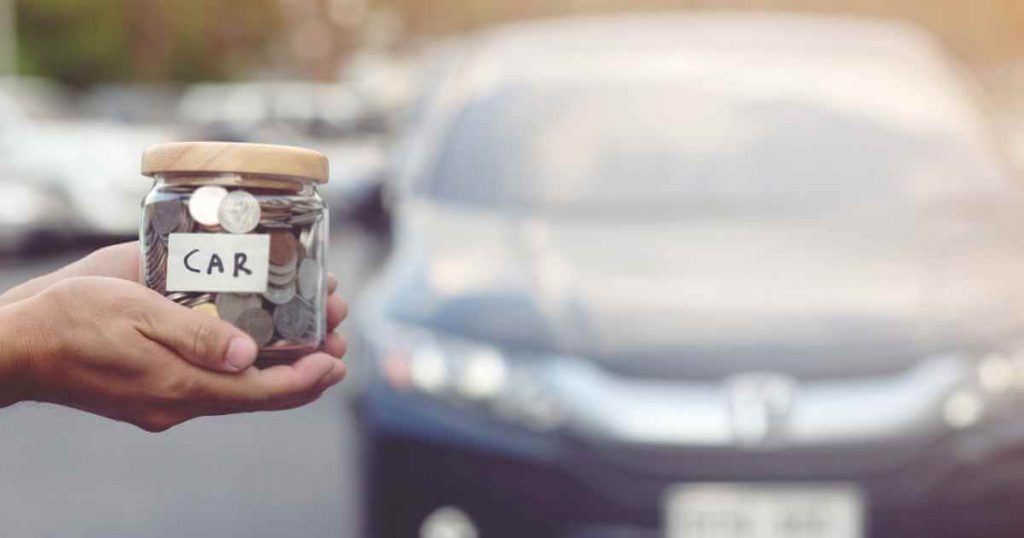 a hand holding a jar with coins and a car in the background showing someone whose prepared after asking do you need credit to buy a car