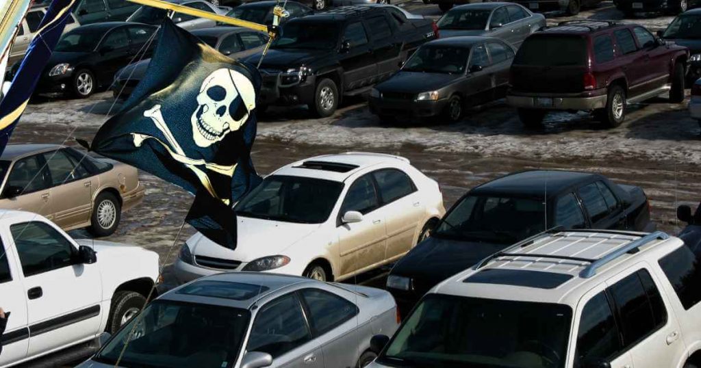 a dirty car lot with a pirate flag showing the warning signs to look for with in house financing dealerships