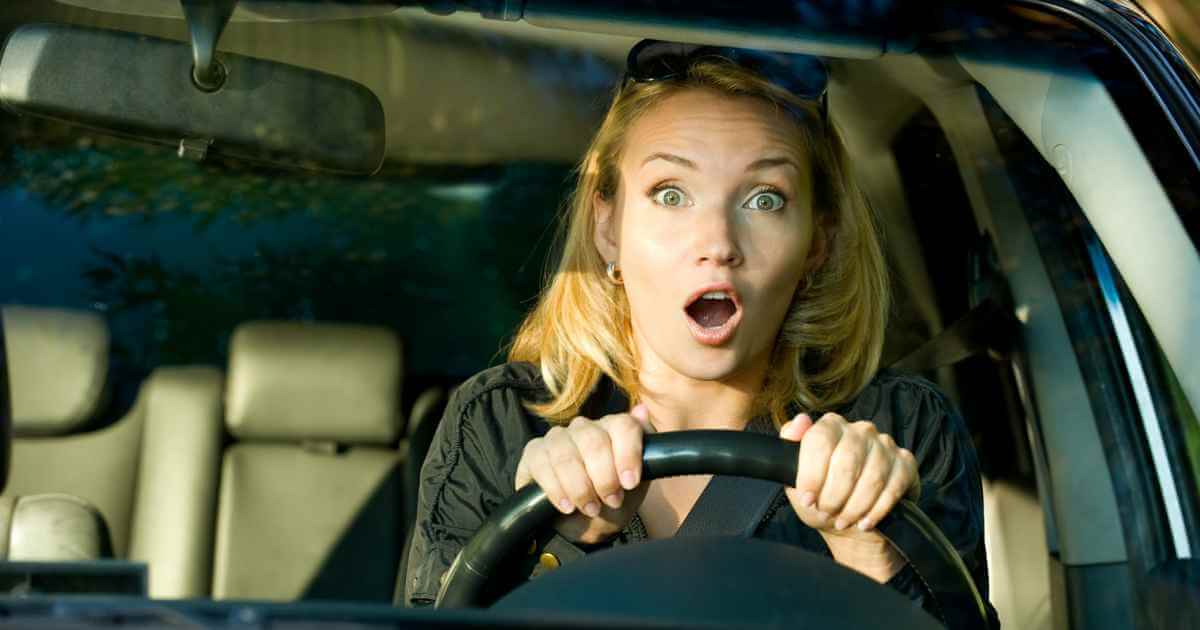 a shocked woman test driving a used car