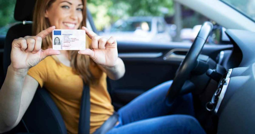 a woman holding up her license showing she's prepared to test drive used cars