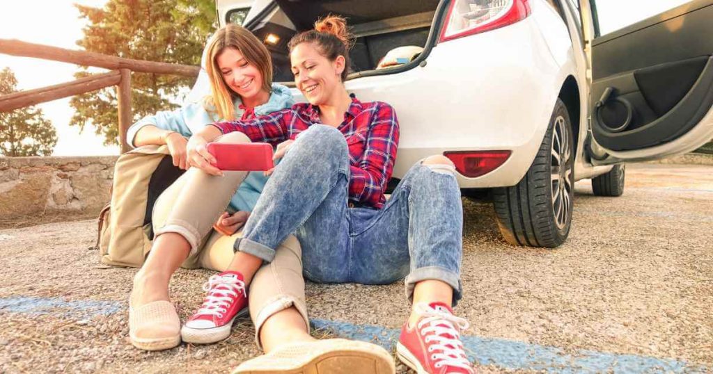 happy friends sitting behind their newly acquired used car bad credit near me