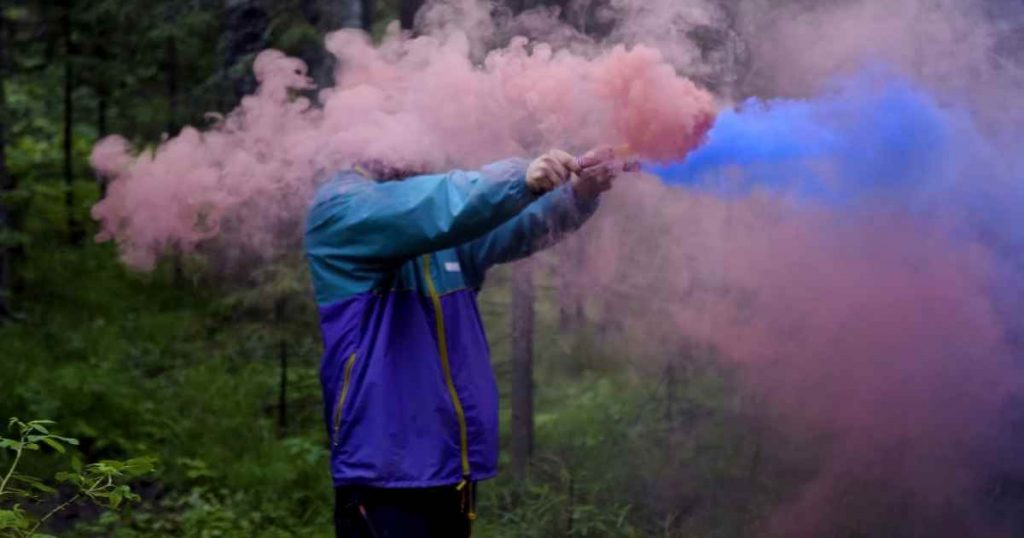 a man holding smoke sticks creating beautiful colors that are demystifying just as the misconceptions surrounding a buy here pay here car dealership have