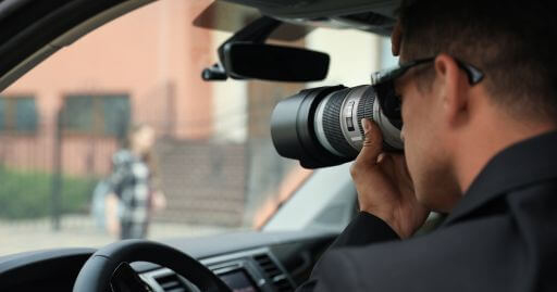 a man inside a car with a giant camera looking at buy here pay here dealerships from the outside