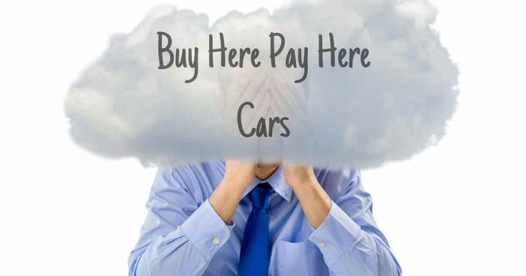 a man rubbing his face that is surrounded by a giant cloud that reads buy here pay here cars