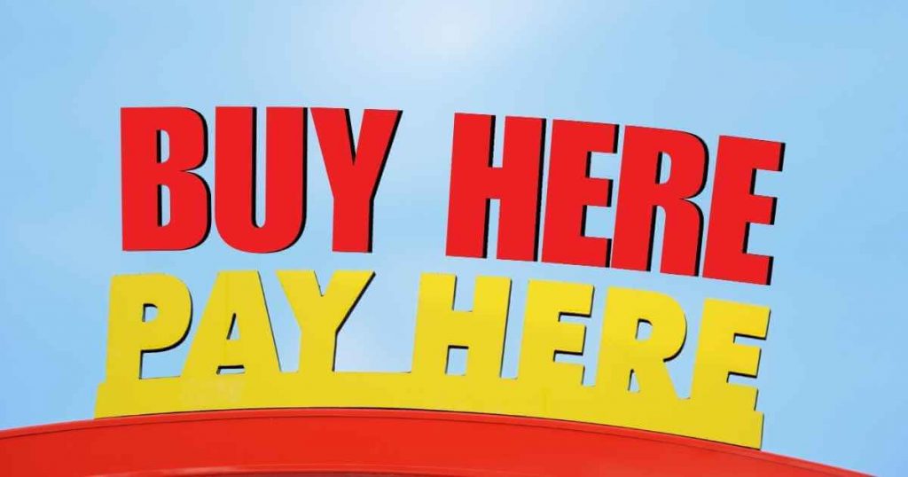 a big yellow and red sign that read buy here pay here