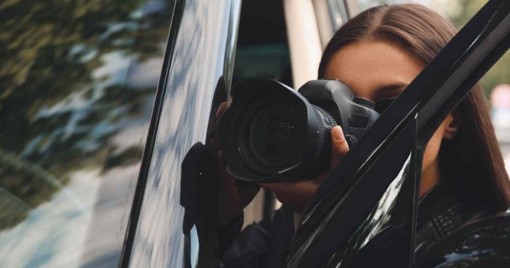 a woman snapping a picture of something next to her car