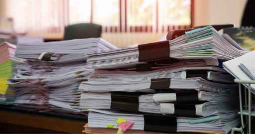 a giant stack of papers neatly organized depicting someone getting all of their proofs and requirements ready to visit a buy pay here dealer.