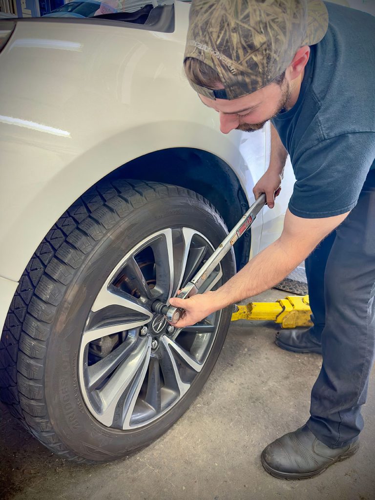 a service technician removing tire lug nuts with a torque wrench