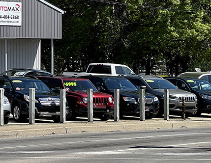 Row of used cars under $10,000 at Automax Indiana dealership lot in South Bend