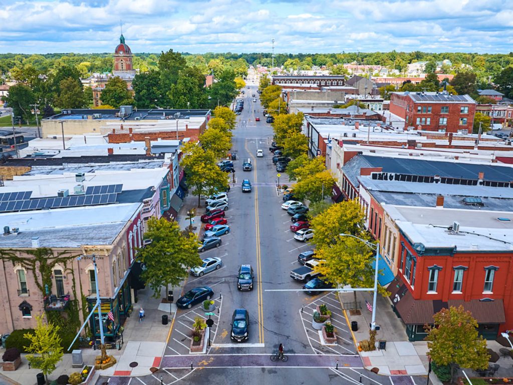 Aerial view of downtown Goshen, Indiana with tree-lined Main Street and the historic courthouse clock tower.