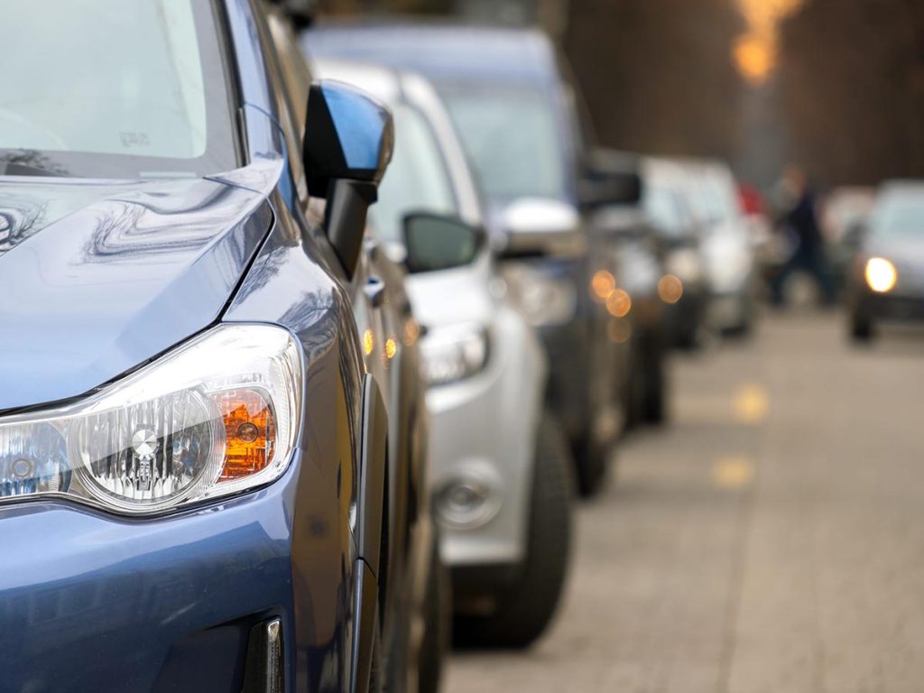 Row of used cars parked closely together on a dealership lot.