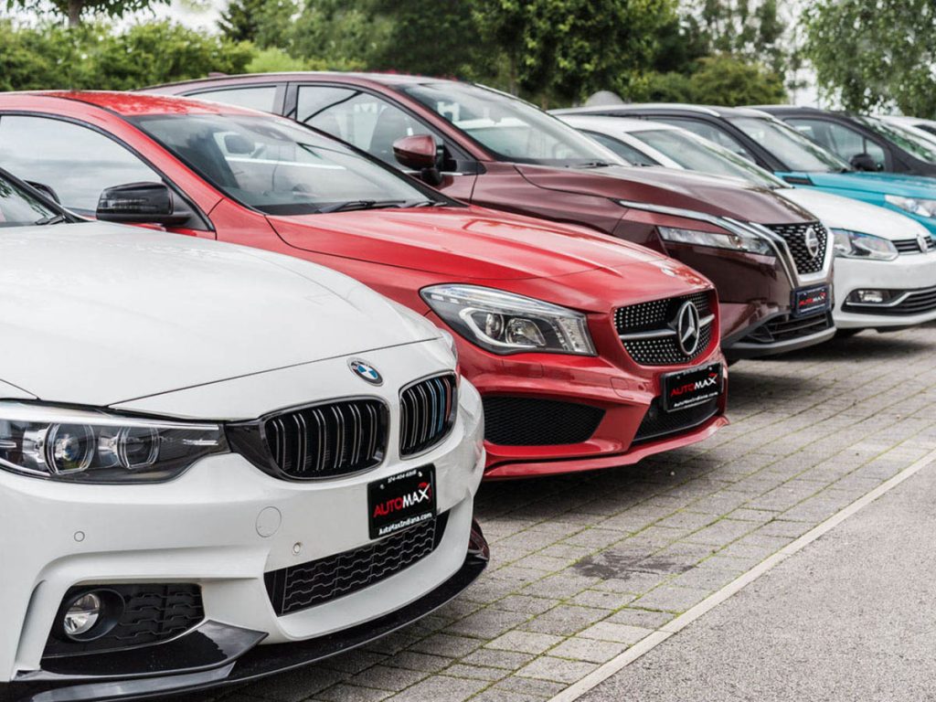 Row of BMW, Mercedes, Nissan and other used cars at Automax of Indiana lot — highly rated dealership in Mishawaka