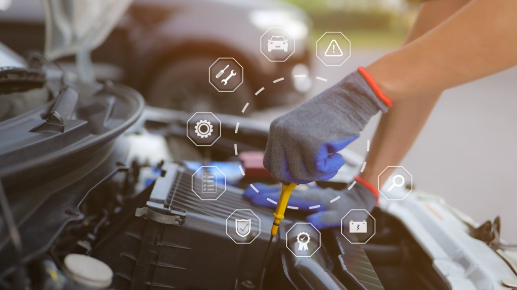 Mechanic checking engine oil dipstick with service icons — used car warranty coverage concept