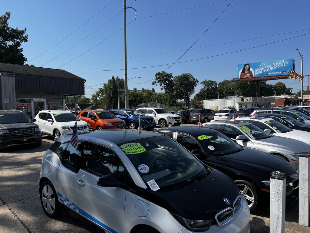 Used cars for sale at Automax Indiana dealership lot in Mishawaka with BMW and Audi sedans displayed with pricing and year stickers