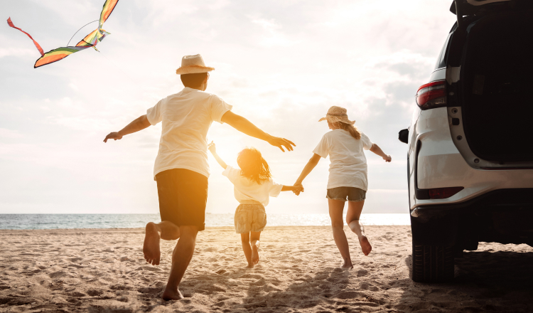 Family running on the beach after exiting their vehicle