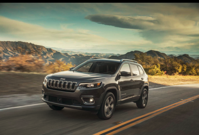Jeep Grand Cherokee SUV in the road by the mountains 