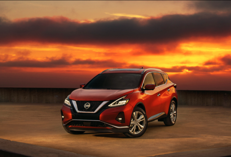 Red Nissan Murano SUV parked with sunset behind it