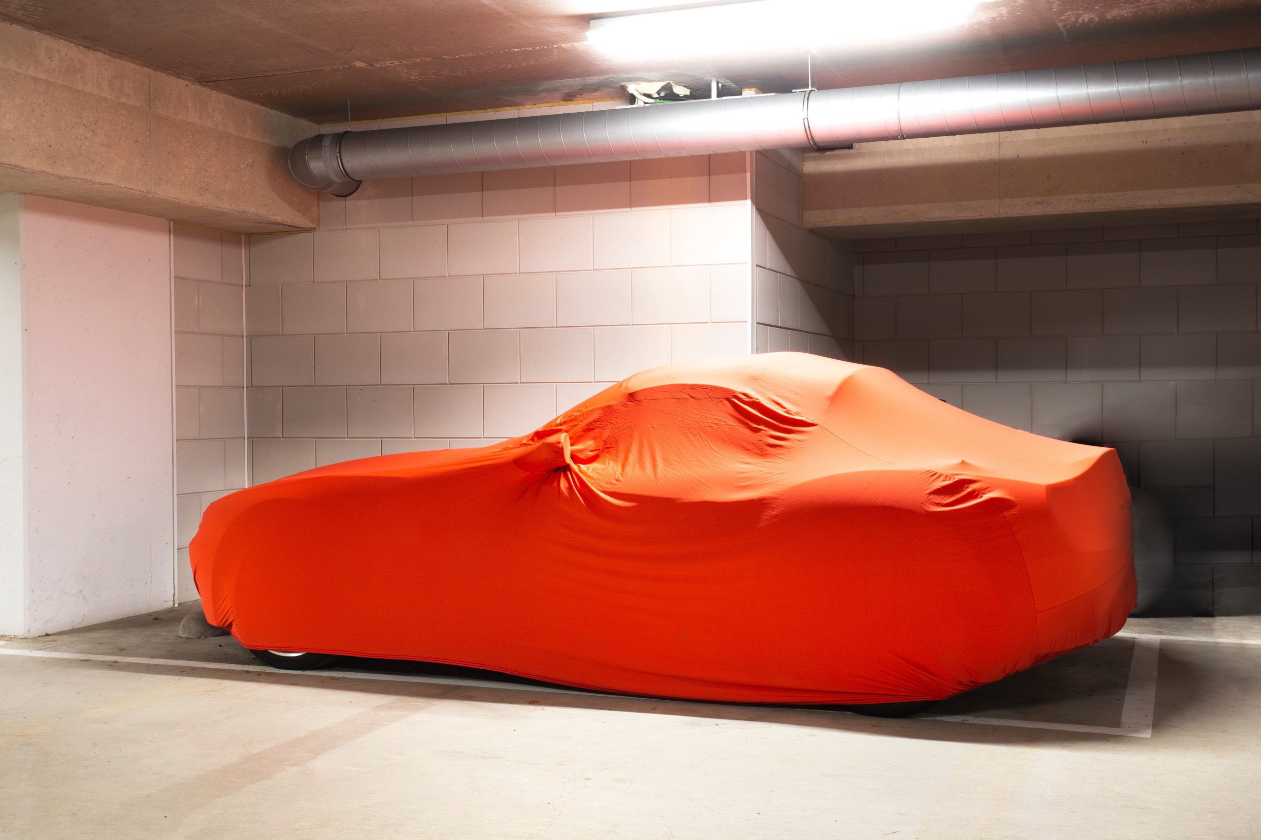 car-protected-with-orange-car-cover-in-garage